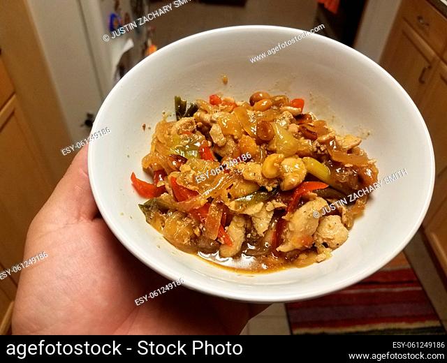 hand holding chicken and onions and peppers Chinese food in bowl