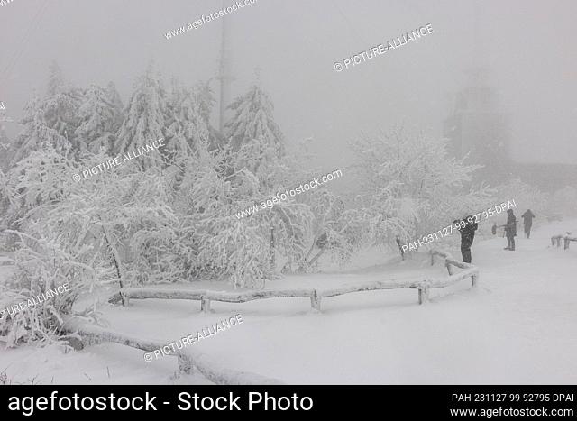 27 November 2023, Hesse, Feldberg: Pedestrians are out and about on the Großer Feldberg in the Taunus in snowfall. Photo: Helmut Fricke/dpa