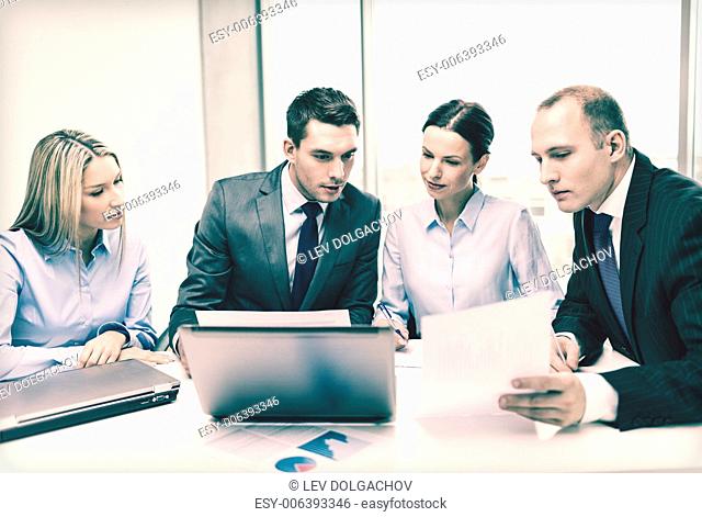 business, technology and office concept - concentrated business team with laptop computers and documents having discussion in office