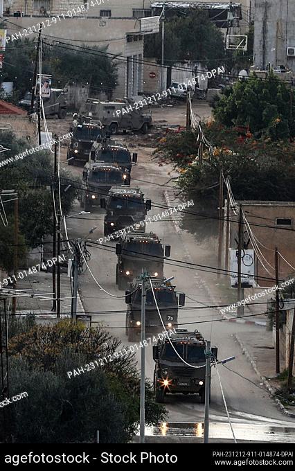 12 December 2023, Palestinian Territories, Jenin: Israeli military vehicles walk on the street during a raid at the Jenin refugee camp