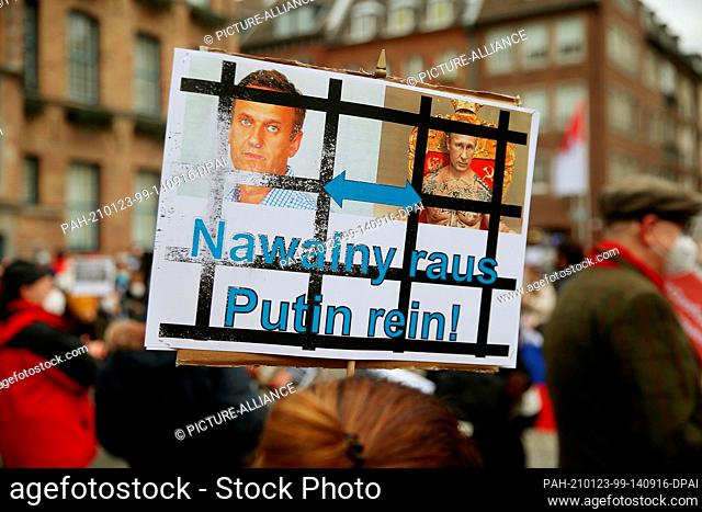 dpatop - 23 January 2021, North Rhine-Westphalia, Duesseldorf: A demonstrator holds a placard in front of the city hall showing bars with the inscription...