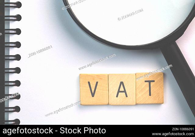 VAT text (Value Added Tax) on scrabble wood pieces isolated on white note pad