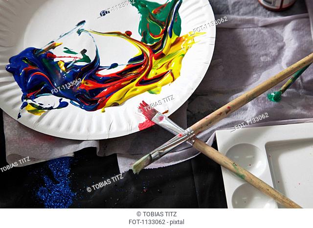 Heaps of acrylic paint on a paper plate and paintbrushes