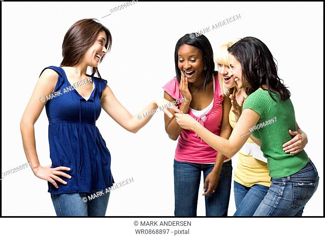 Three women looking at other womans engagement ring smiling