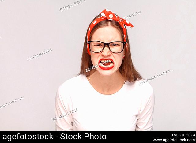 angry face screaming portrait of anger crazy bossy emotional young woman in white t-shirt with freckles, black glasses, red lips and head band