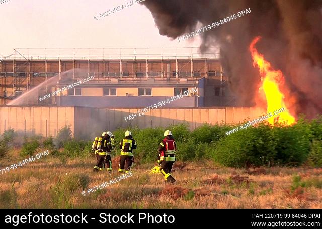 19 July 2022, Brandenburg, Premnitz: Firefighters extinguish a fire at a chemical plant. In a warehouse of a chemical fiber producer in the Havelland district