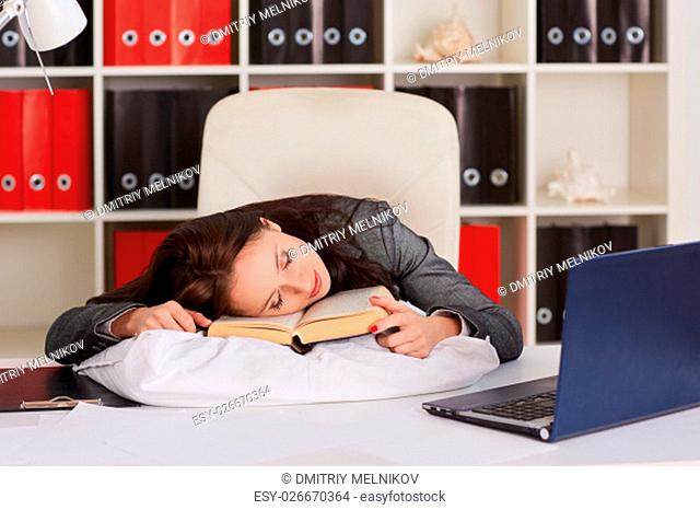 Tired young business woman is sleeping on workplace in the office