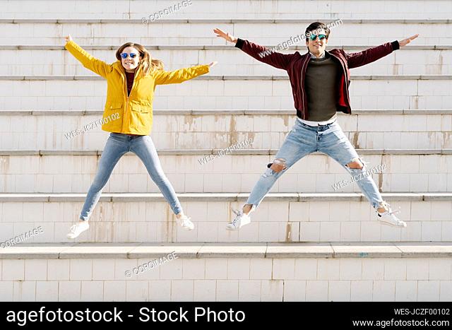 Happy young couple jumping on stairs