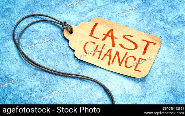 Last chance - handwriting on paper price tag with a twine against textured blue bark paper, marketing and shopping offer concept