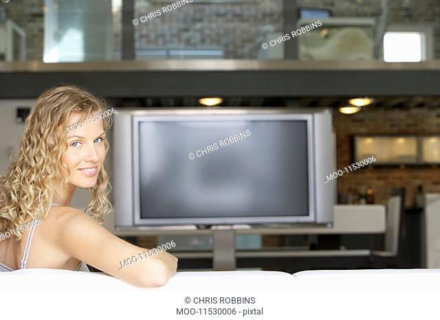 Woman sitting in modern living room plasma television in background portrait