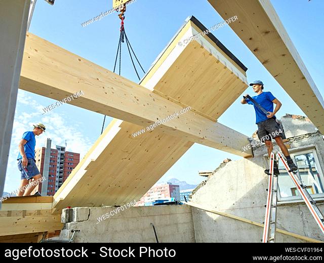 Workers working at construction site on rooftop of house