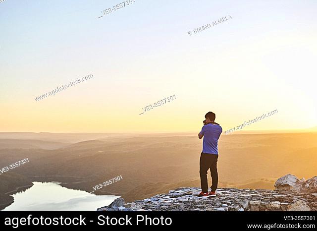 Young man taking pictures to sunset in Monfragüe National Park, Extremadura (Spain)