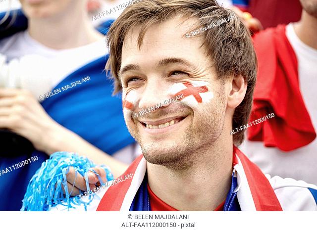 British football fan smiling cheerfully at match, portrait