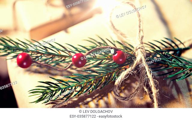 christmas, holidays, presents, new year and decor concept - close up of gift box wrapped into brown mail paper and decorated with fir brunch and rope bow