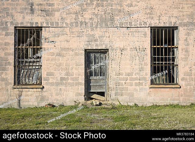 Abandoned jailhouse facade, an empty building with barsont the windows