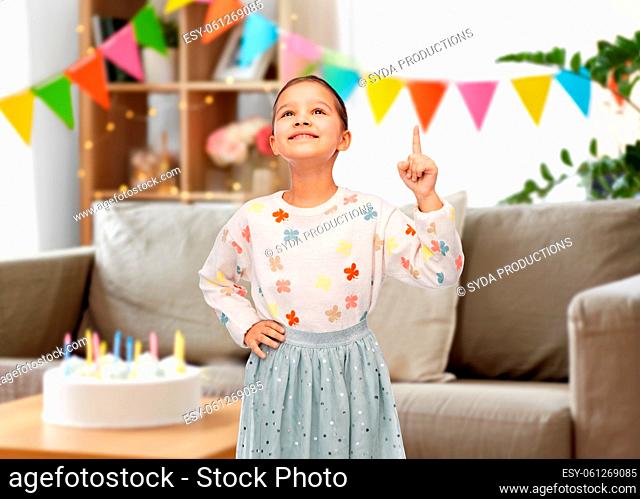 happy girl pointing finger up at birthday party