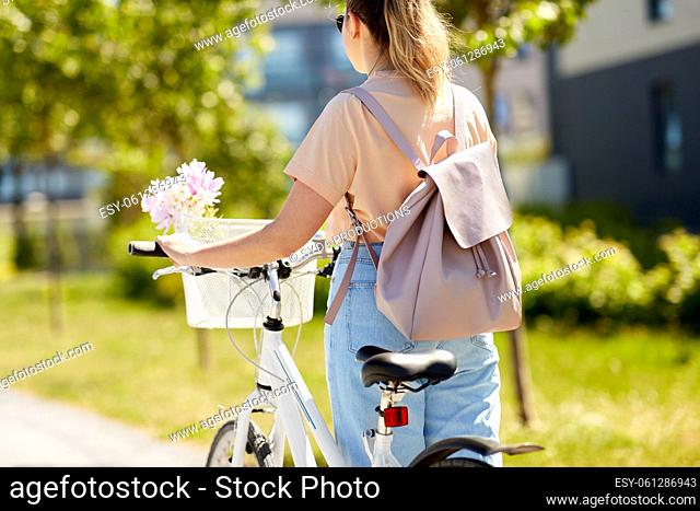 woman with bicycle and backpack walking in city