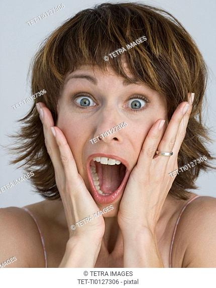 Woman looking surprised with hands on cheeks