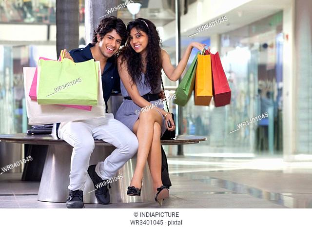 Handsome young couple showing shopping bags at mall