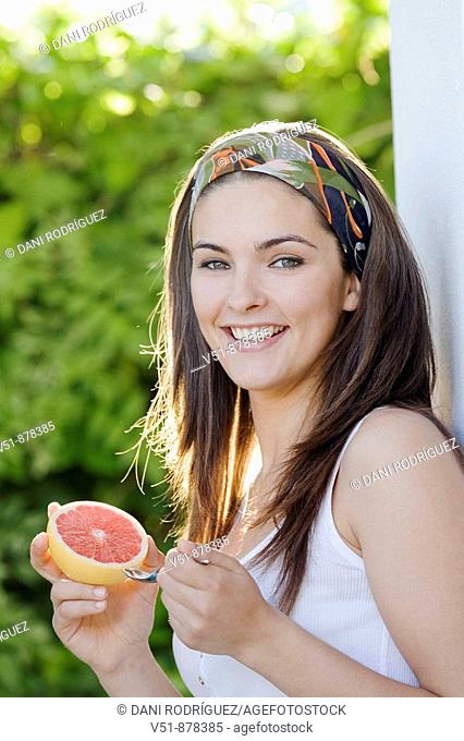 Woman with a piece of fruit smiling and looking at camera