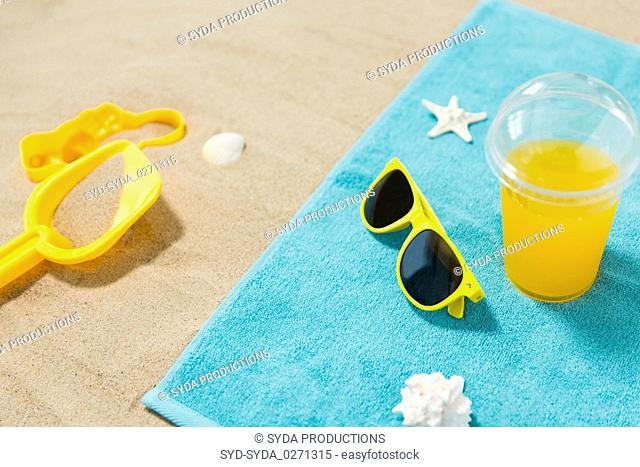 sunglasses, sand toys and juice on beach towel