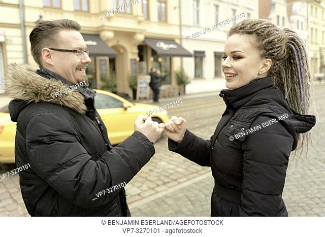 man and woman hooking their small fingers at street, making promises, in inner cultural historic city, in Cottbus, Brandenburg, Germany