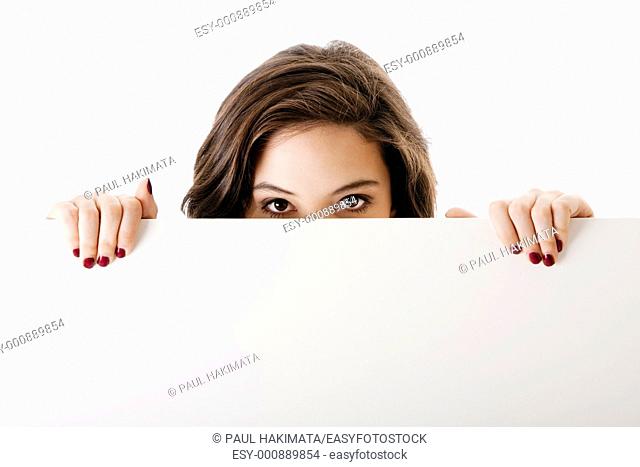 Partial face of beautiful young caucasian brunette business student woman holding a white blank board, isolated