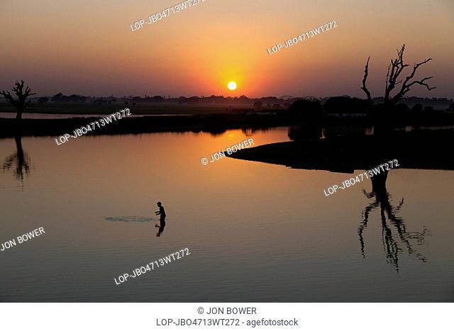 Myanmar, Mandalay, Lake Taungthaman. A fisherman on Taungthaman Lake in Myanmar at sunset viewed from U Bein Teak Bridge