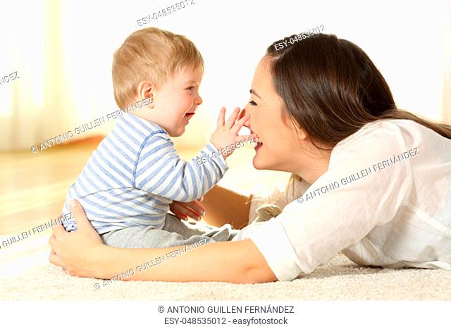 Affectionate mother and baby playing together on a carpet on the floor at home