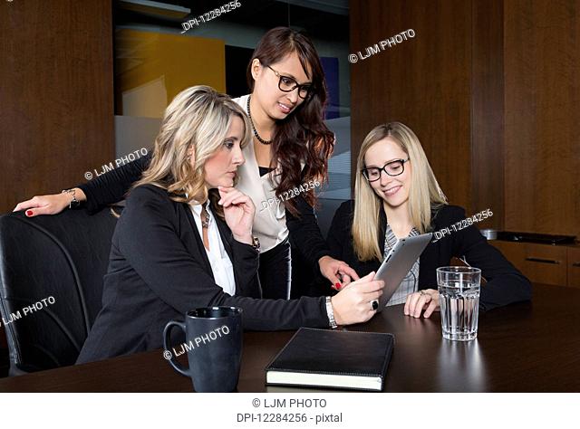 Three professional business women during a training session in a boardroom; St. Albert, Alberta, Canada