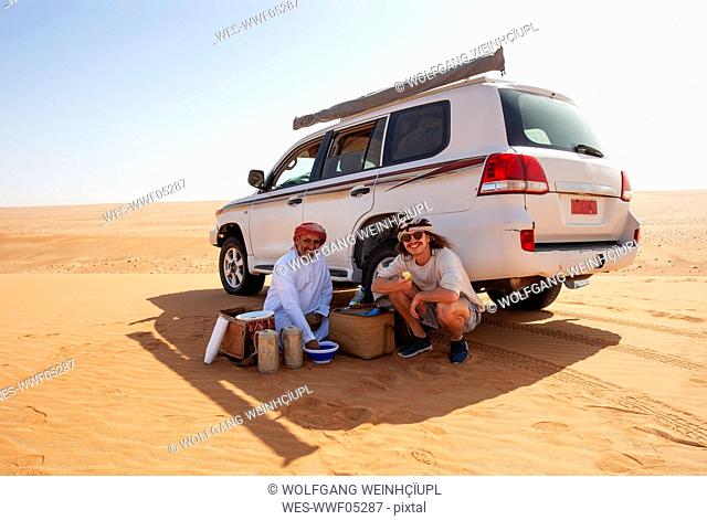 Tourist having a coffee break with his local driver in the desert, Wahiba Sands, Oman