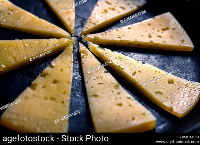 Pieces of cheese are laid out in the form of sunlight on a black cast-iron surface