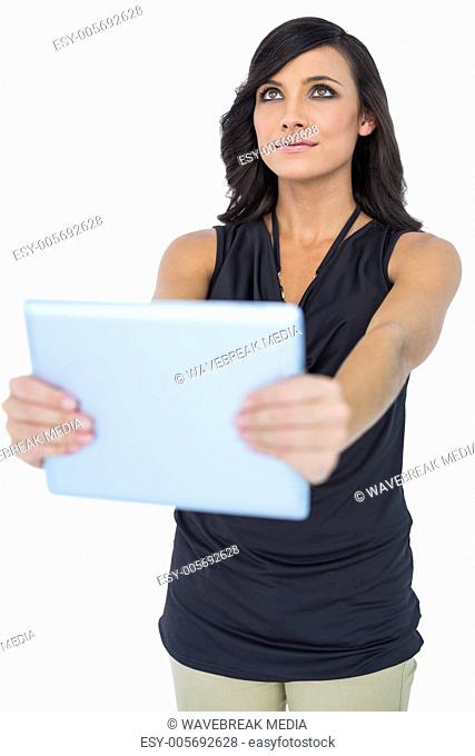 Elegant dark haired model holding tablet looking up