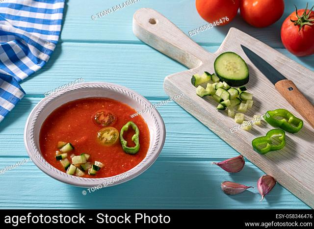 Gazpacho Andaluz is an Andalusian tomato cold soup from Spain with cucumber, garlic, pepper on light blue background