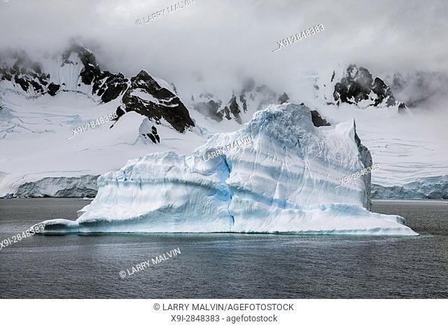Iceberg along the Antarctica Peninsula with mountain backdrop