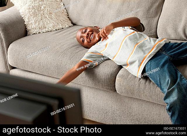 Boy lying on sofa watching tv