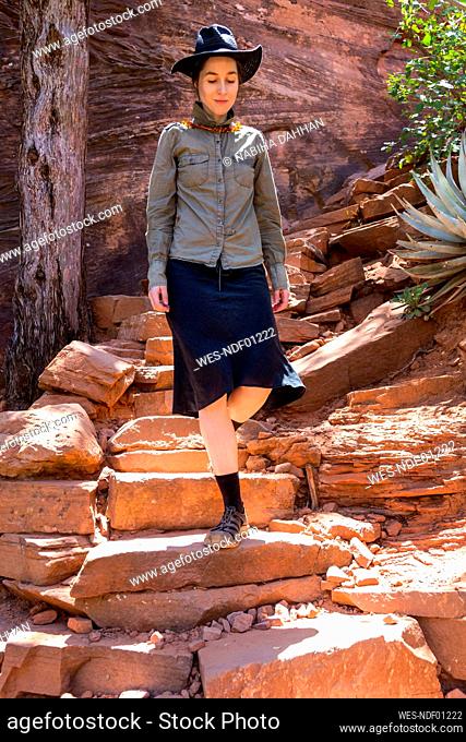 Female hiker walking down on red rocks, Sedona, Arizona, USA
