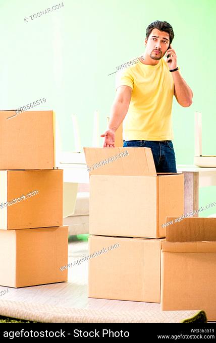 Young handsome man moving in to new house with boxes