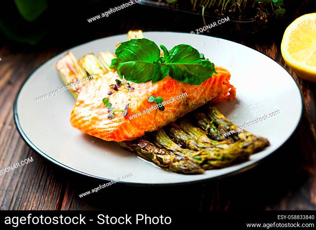 Grilled salmon and asparagus on the white plate. Backed fish fillet with green asparagus, healthy food close up