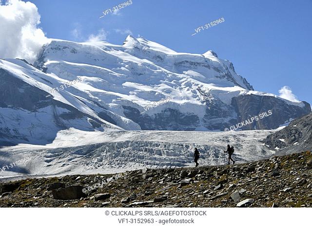 Trekkers with huge glacier behind, Grand Combin North Face, path to Panossiere hut, Switzerland, Swiss