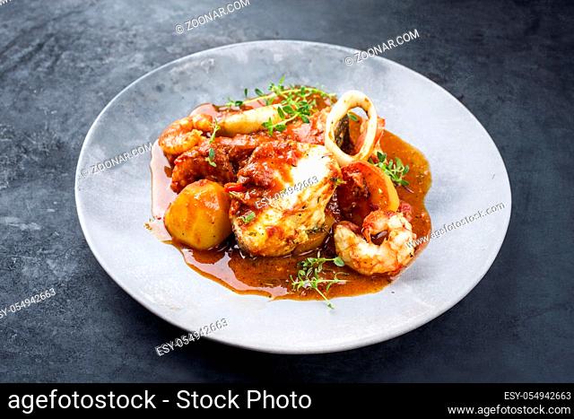 Traditional Brazilian fish stew moqueca capixaba with fish filet and king prawns in tomato sauce as closeup on a modern design plate