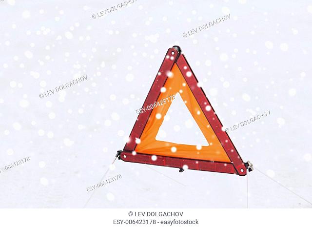 transportation and winter concept - closeup of warning triangle on snow