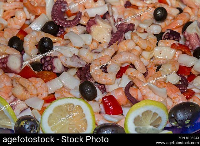Meeresfrüchtesalat aus Krabben und Tintenfischstücken garniert mit schwarzen Oliven