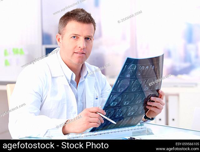 Middle-aged doctor studying x-ray image in office