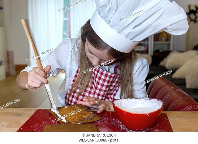 Girl preparing gingerbread house