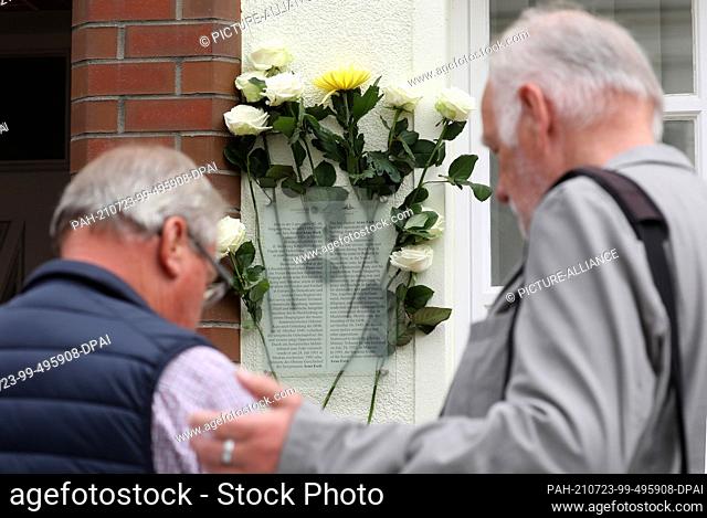 23 July 2021, Mecklenburg-Western Pomerania, Rostock: Flowers are stuck behind a memorial plaque for Arno Esch, who was executed by the Soviet regime 70 years...