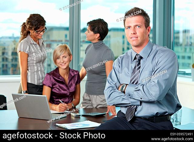 Confident businessman at office with business team in background