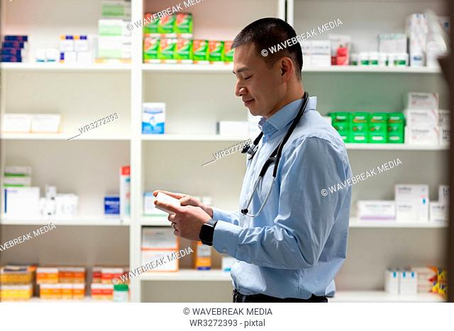 Young asian male doctor holding medicine and standing in clinic