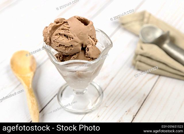 Close up of a glass dish of a few scoops of chocolate ice cream