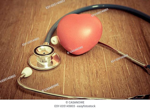 Red heart and stethoscope on wooden background